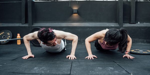 Two adults doing push-ups in an indoor gym setting in Mexico City, promoting a fit and healthy lifestyle.