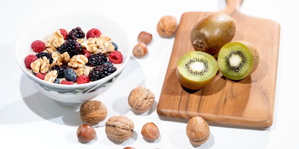 A vibrant bowl of mixed berries, walnuts, and kiwi on a cutting board. Perfect for a healthy breakfast.
