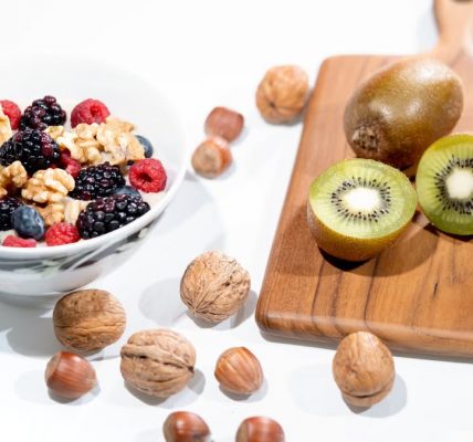 A vibrant bowl of mixed berries, walnuts, and kiwi on a cutting board. Perfect for a healthy breakfast.