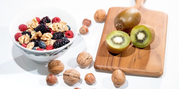A vibrant bowl of mixed berries, walnuts, and kiwi on a cutting board. Perfect for a healthy breakfast.